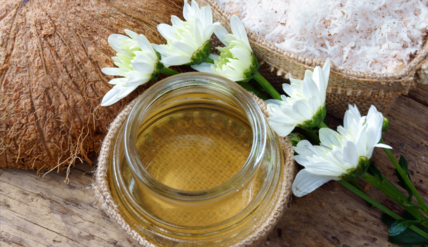 Coconut oil in a glass jar is displayed next to a coconut shell